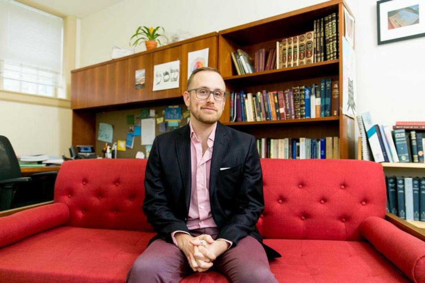 Rabbi Alex Weissman sitting on a sofa in front of a bookshelf
