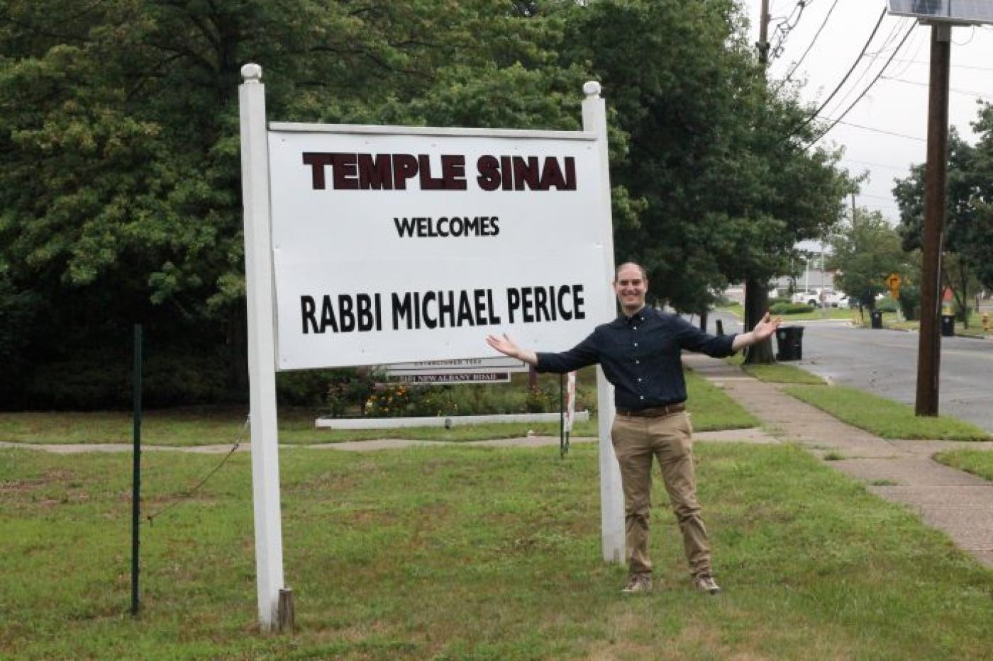 Rabbi Michael Perice stands with the sign his congregation at Temple Sinai installed to welcome him. Perice, the synagogue’s newest rabbi, started his new position July 1.