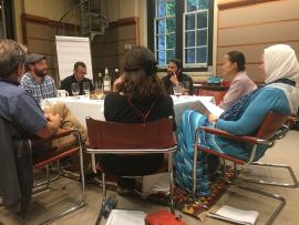 People in Muslim, Christian, Jewish garb seated together at a Shabbat table