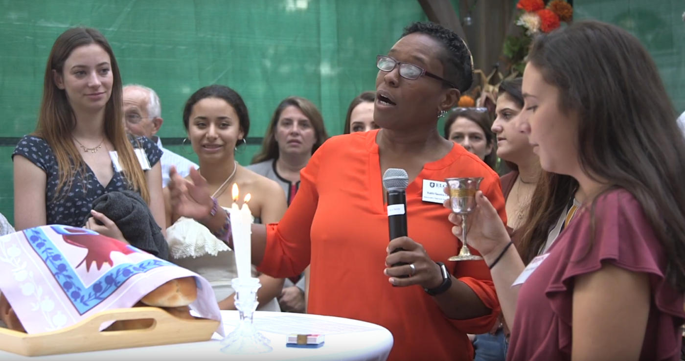 Rabbi Sandra Lawson leading Friday night prayers surrounded by Elon University college students