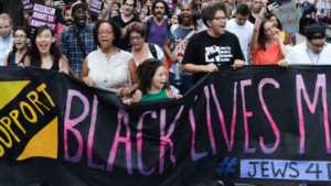 Protesters at a rally hold a Jews 4 Black Lives matter banner.