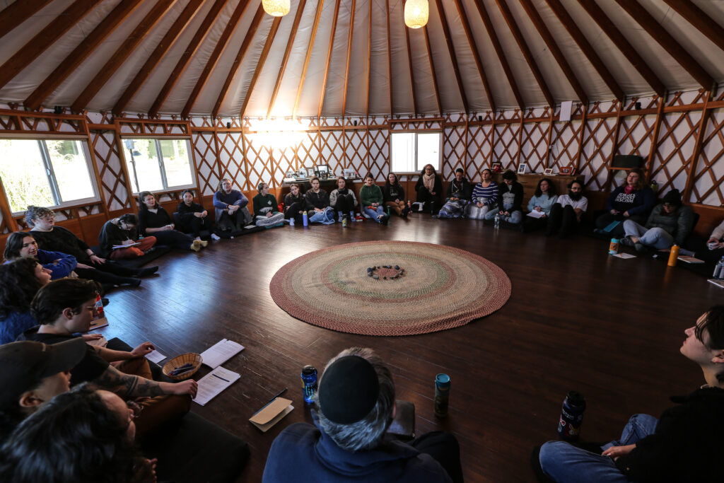 Participants in a grief retreat sit in a circle inside a yurt